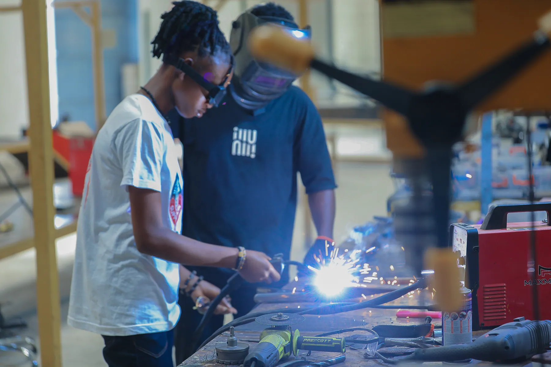 Girl practising welding safely under expert supervision